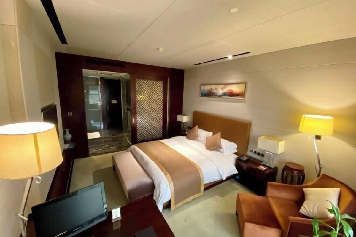 Ein Hotelzimmer mit Bett, Nachttischlampen, Fernseher, Schreibtisch und Stuhl.