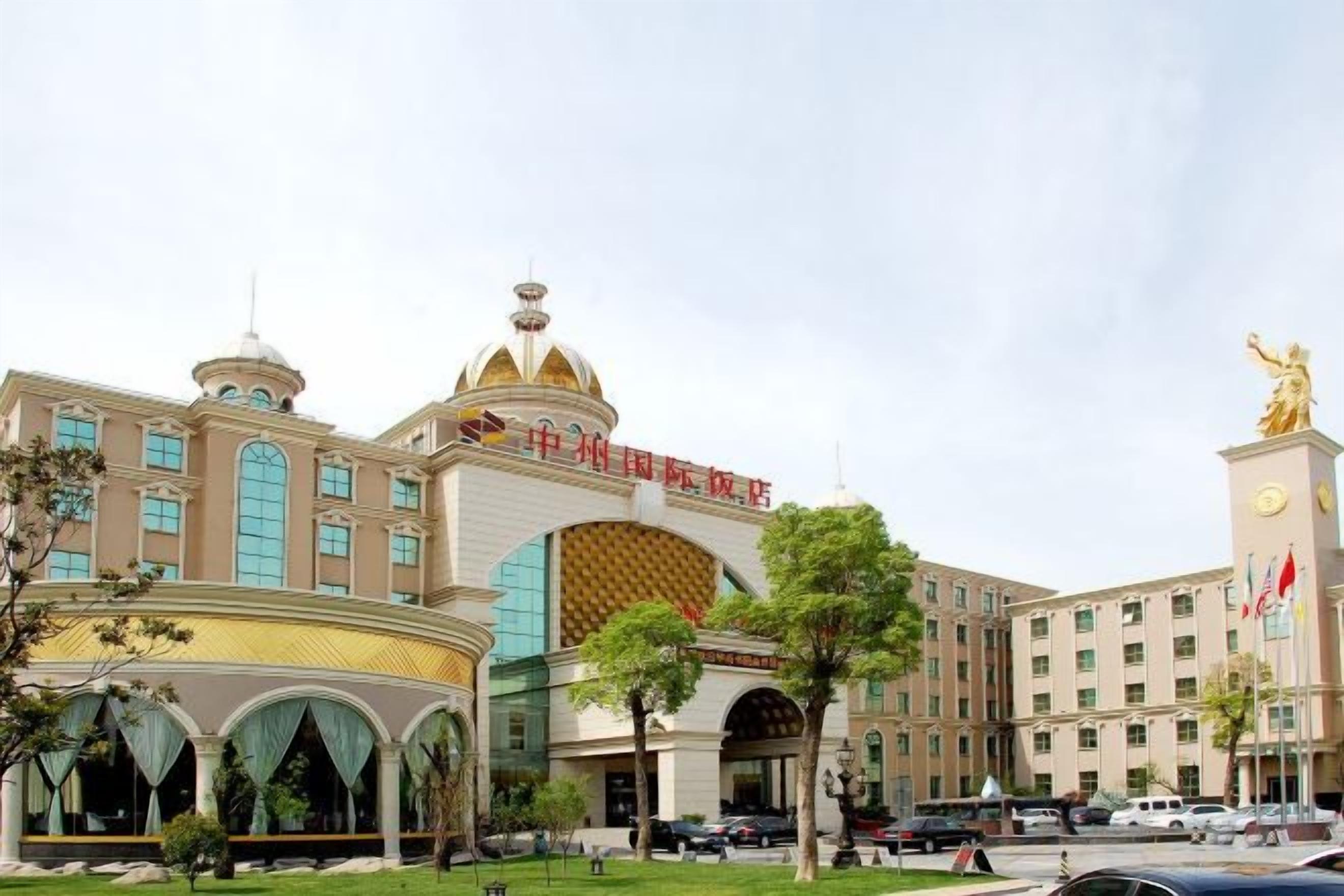 Ein Hotel mit großzügigem Eingangsbereich, mehreren Etagen und einer markanten goldenen Statue.