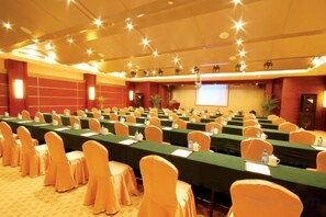 A conference room with rows of tables, chairs, and a projection screen. - Zhongzhou International Hotel Kaifeng (Kaifeng)