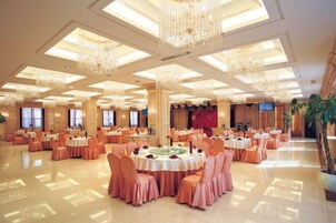 Un salón de banquetes con mesas redondas, sillas y candelabros.