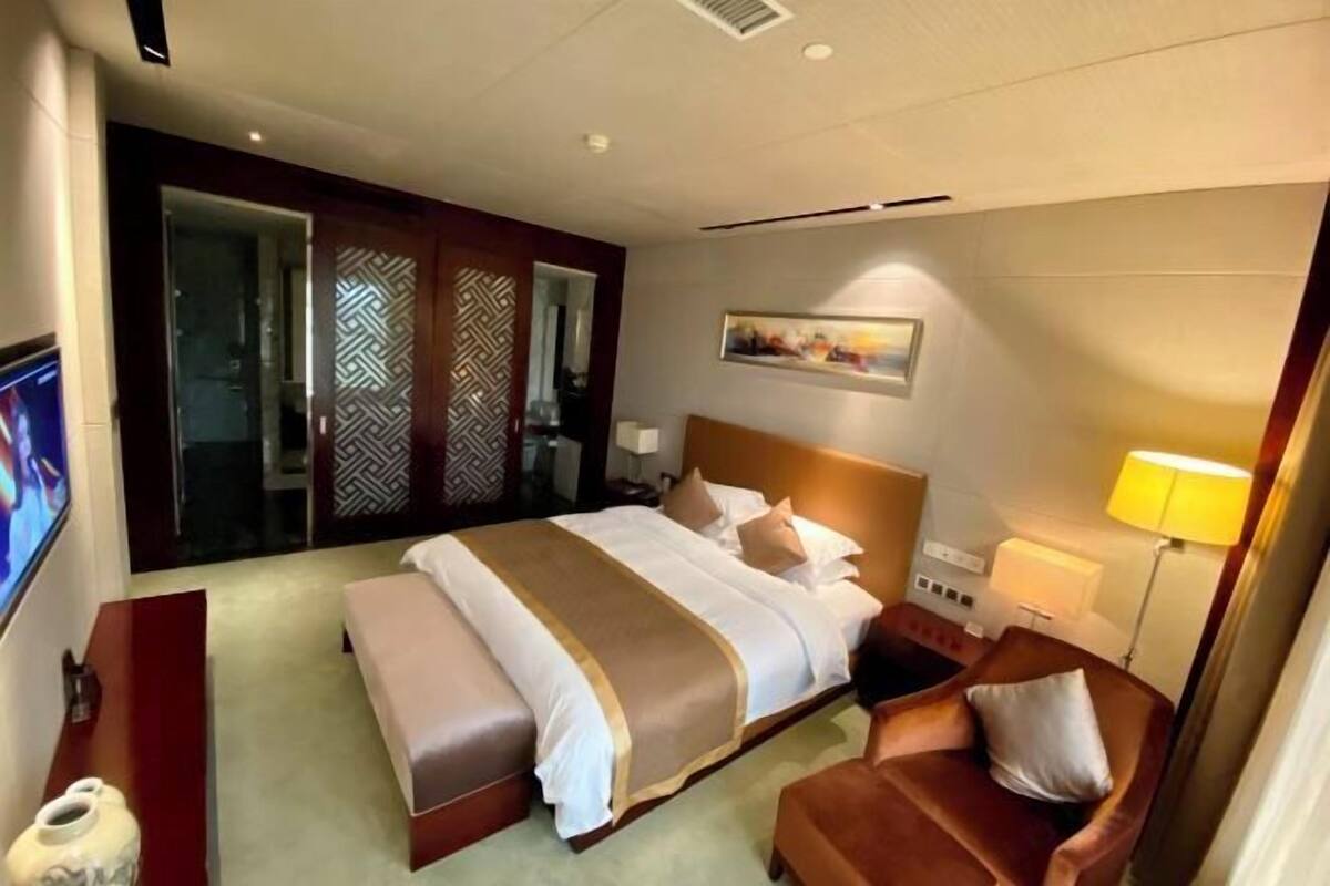 Ein Hotelzimmer mit Bett, Sofa, Fernseher, Lampe und einer Wanddekoration.