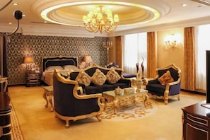 A luxurious bedroom with a large bed, ornate furniture, and a chandelier.