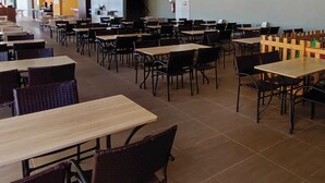 Eine Cafeteria mit mehreren Tischen und Stühlen, die in Reihen angeordnet sind.