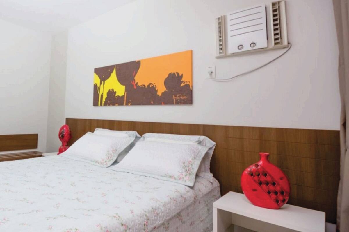 Ein Hotelzimmer mit Bett, Nachttisch, Wandheizung und einem Gemälde.