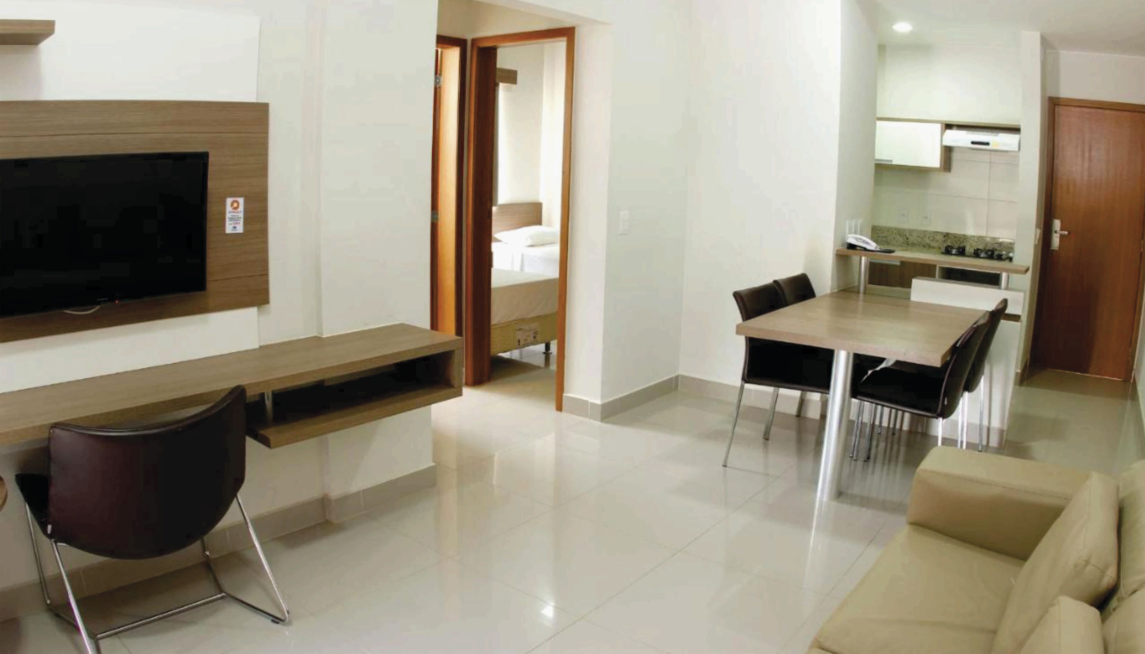 A modern living room with a flat-screen TV, a wooden console table, a sofa, and a dining area with a table and chairs.