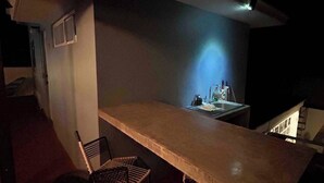 A dimly lit outdoor bar area with a long counter, two chairs, and a sink. - Bugambilias 203 - Private Room with parking and a big terrace only for you (Santa Lucía del Camino)