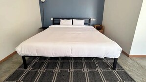 A hotel room with a large bed, a nightstand, a lamp, and a blue accent wall. - Bugambilias 203 - Private Room with parking and a big terrace only for you (Santa Lucía del Camino)