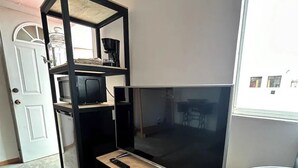 A compact room with a built-in TV on a wooden shelf, a small desk with a chair, and a white door. - Bugambilias 203 - Private Room with parking and a big terrace only for you (Santa Lucía del Camino)