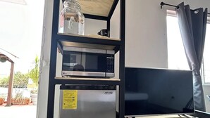 A compact kitchenette with a microwave, refrigerator, and shelf unit. - Bugambilias 203 - Private Room with parking and a big terrace only for you (Santa Lucía del Camino)