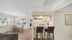 A modern kitchen with a dining area, large windows, and a view of the outdoors. - Two lakefront homes on one property near Salt Springs with great porches & yard (Salt Springs)