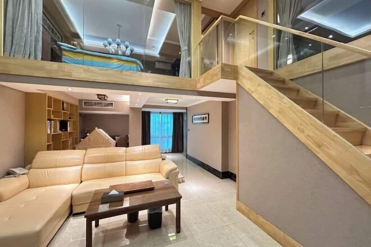 A modern living room with a sofa, coffee table, and a staircase leading to an upper level.