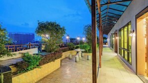 A covered outdoor walkway with a tiled floor, benches, and planters. - Jinpin Feicui Hotel (Pingzhou Yuqijie Subway Station Branch Pingnan) (Foshan)