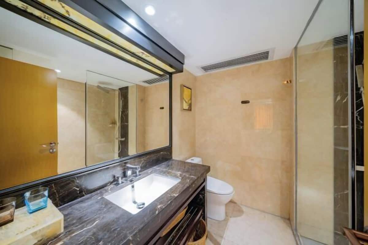 A modern bathroom with a large mirror, a sink, a toilet, and a shower area.