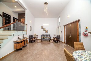 Uma sala espaçosa com escada, sofá e mesa de jantar.
