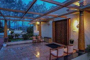 Uma área externa coberta com pérgula de madeira, assentos e vista para a paisagem ao redor.