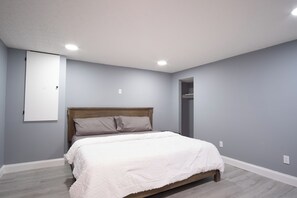 Une chambre à coucher avec un lit, une tête de lit en bois et un mur blanc.