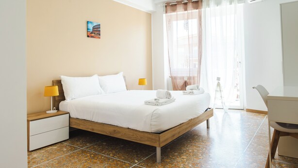 A bedroom with a wooden bed, two bedside tables with lamps, a desk, and a chair. - Domus Angelina - Two Bedroom Apartment, Sleeps 4 (Rome)