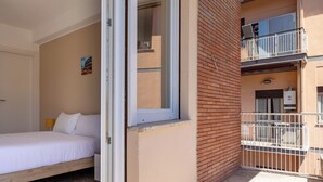 A bedroom with a bed, a window, and a balcony with a white railing. - Domus Angelina - Two Bedroom Apartment, Sleeps 4 (Rome)