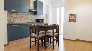 A modern kitchen with dark blue cabinets, a microwave, and a dining table with four chairs. - Domus Angelina - Two Bedroom Apartment, Sleeps 4 (Rome)
