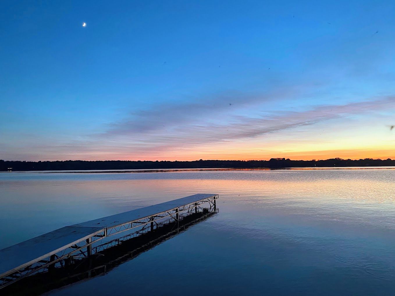 A calm body of water with a dock extending into it.
