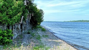 Une côte rocheuse bordée d’une végétation luxuriante et donnant sur une étendue d’eau calme.