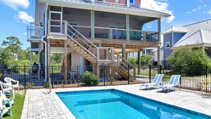 Ett tvåvåningshus med en swimmingpool, utomhusmöbler och en inhägnad uteplats.