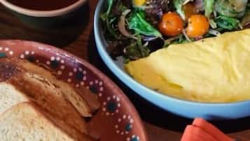 A plate with toast, a small bowl of butter, and a salad with cherry tomatoes.
