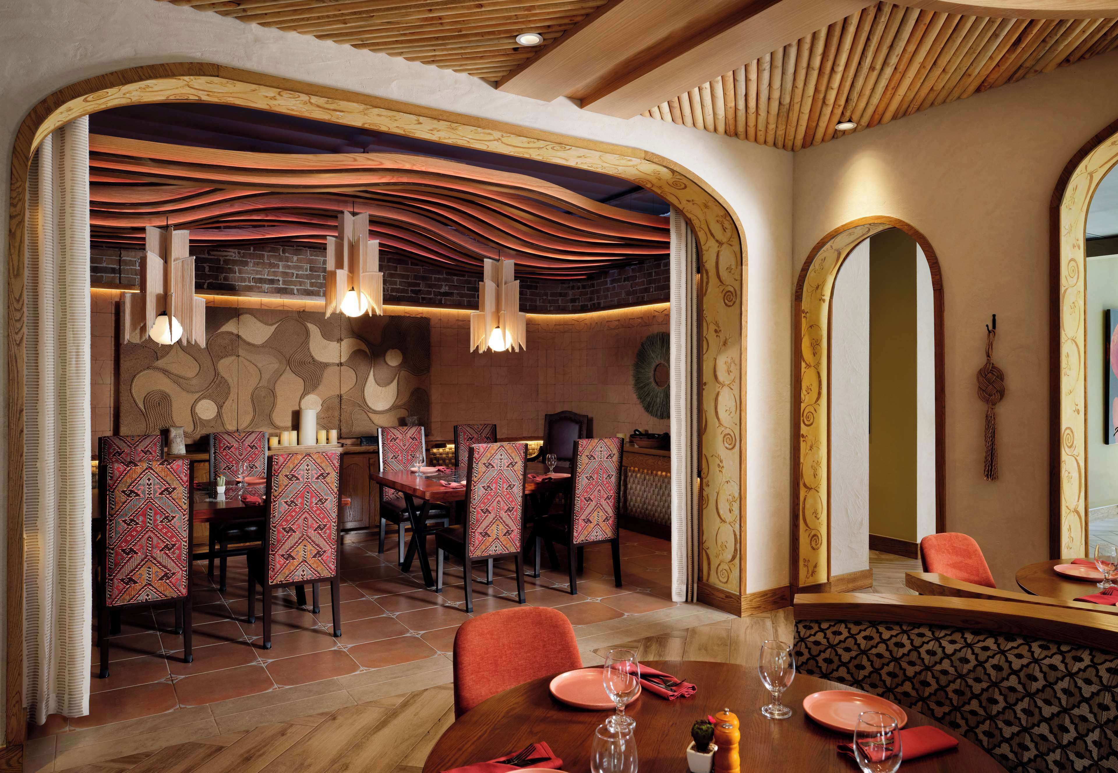Ein Restaurant mit modernem Interieur, inklusive Backsteinwand, Holzboden und gemusterten Stühlen.