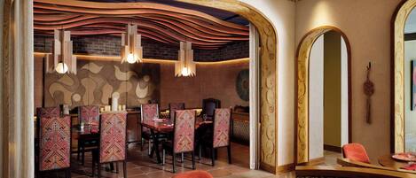 Ein Restaurant mit modernem Interieur, inklusive Backsteinwand, Holzboden und gemusterten Stühlen.