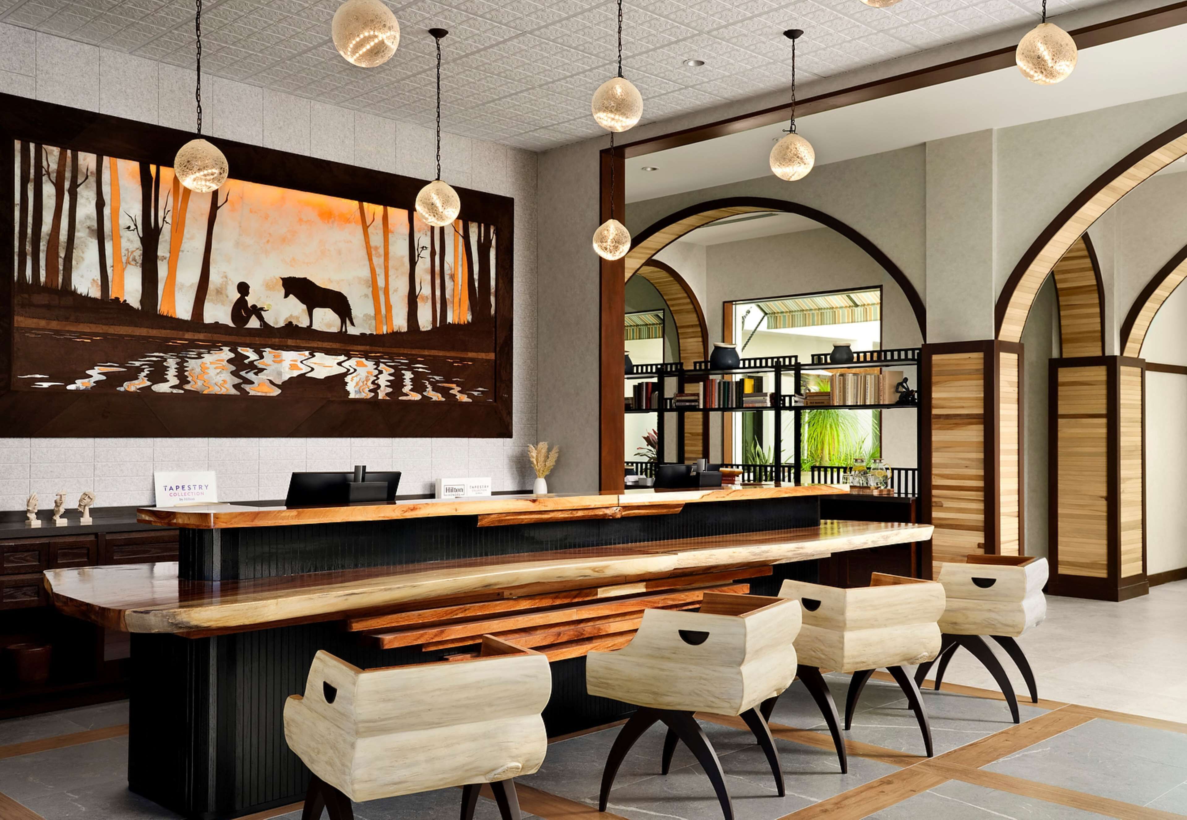 A modern bar area with a wooden counter, bar stools, and pendant lighting.