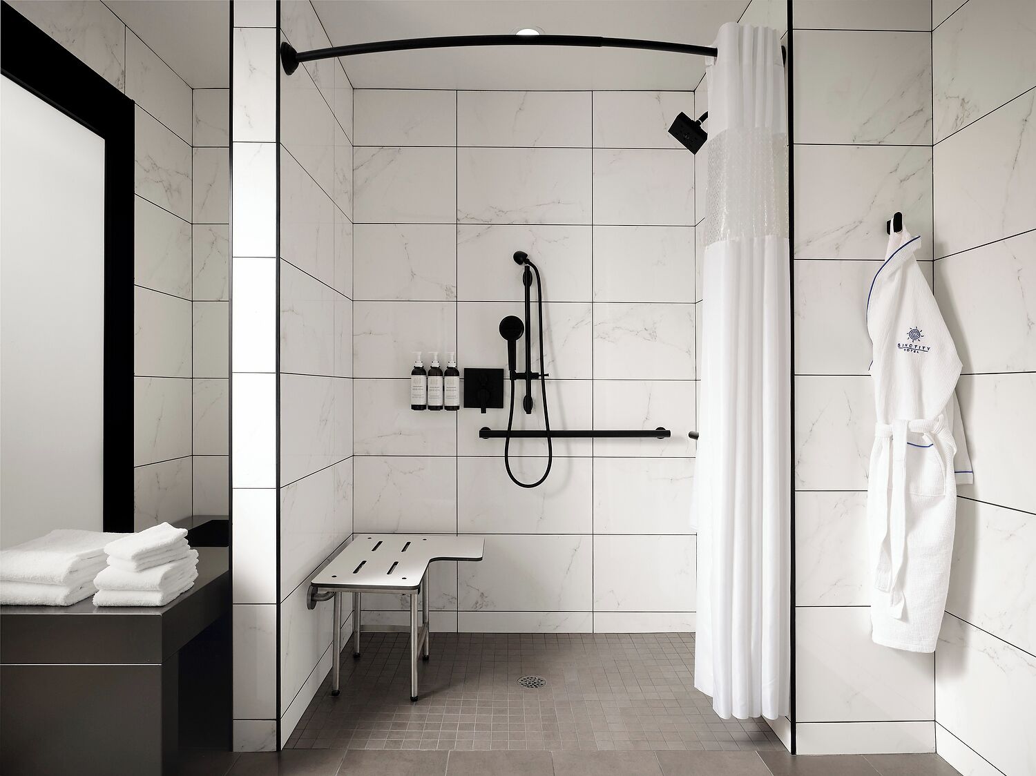 A modern bathroom with a shower, a towel rack, and a small table.