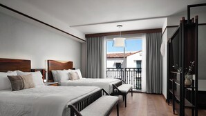 Une chambre d’hôtel avec deux lits, un balcon et vue sur l’immeuble.