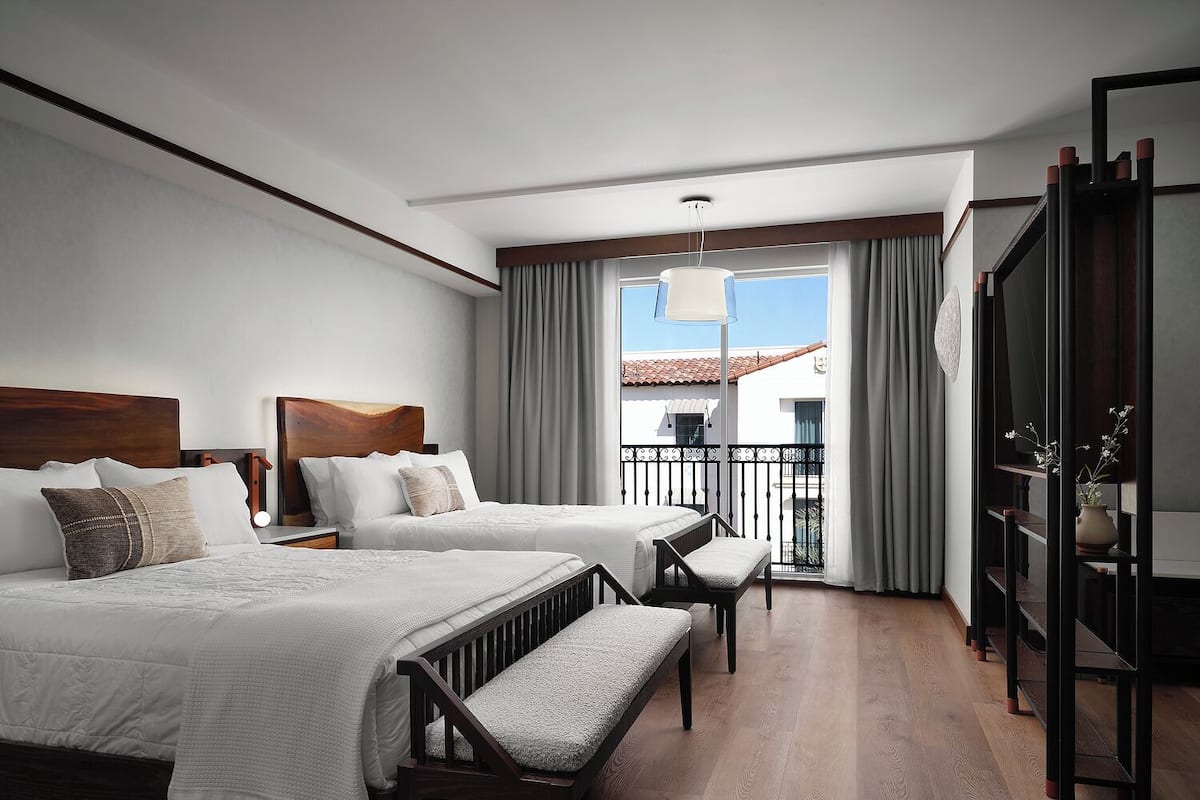 A hotel room with two beds, a balcony, and a view of the building.
