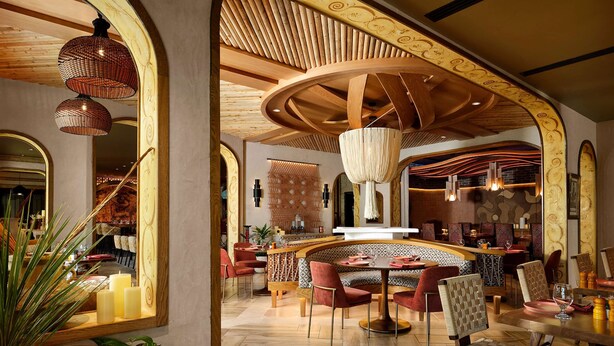 Un interno moderno con una zona salotto centrale, soffitto in legno e illuminazione decorativa.