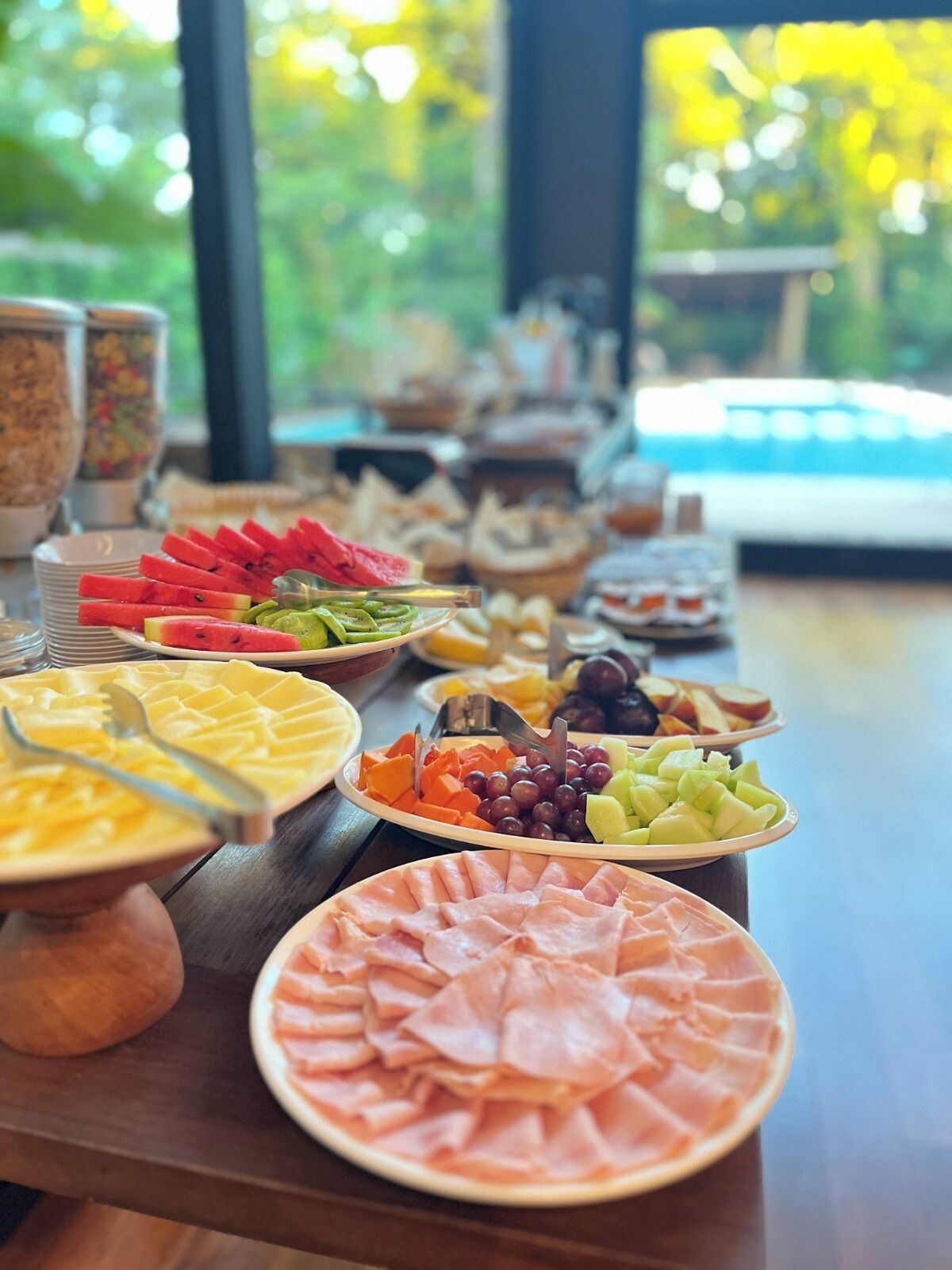 A buffet table with various food items including sliced fruits, cheeses, and meats.