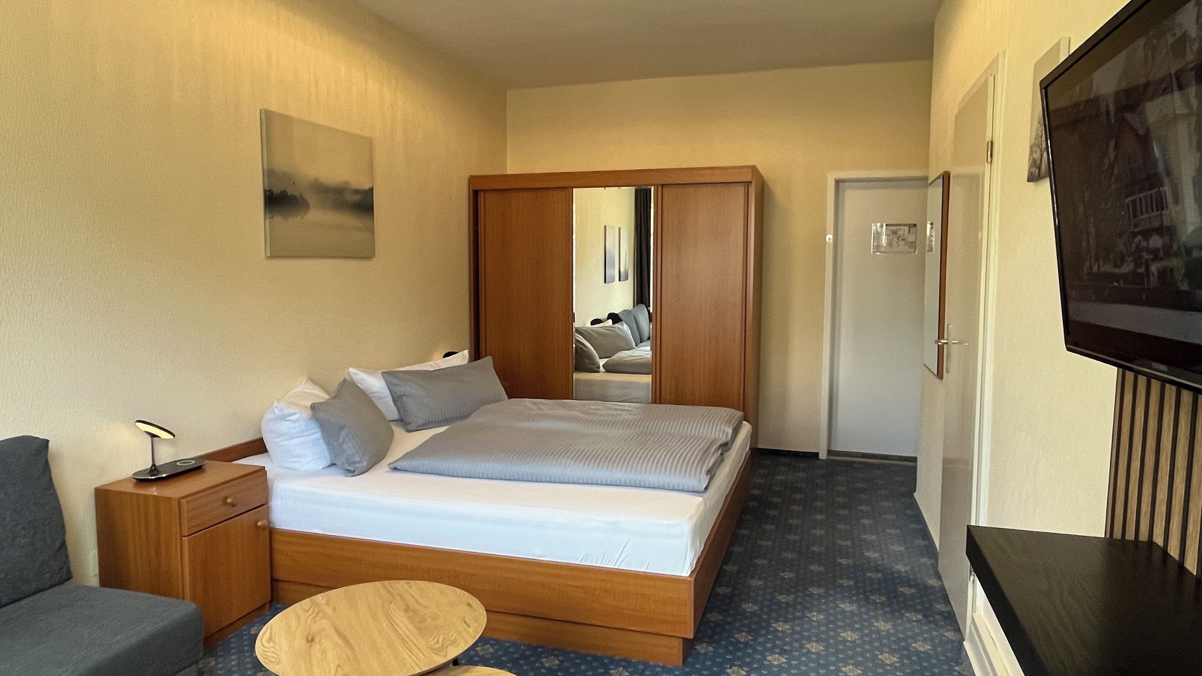 Une chambre d’hôtel équipée d’un lit, d’une table de chevet, d’une lampe et d’un téléviseur.