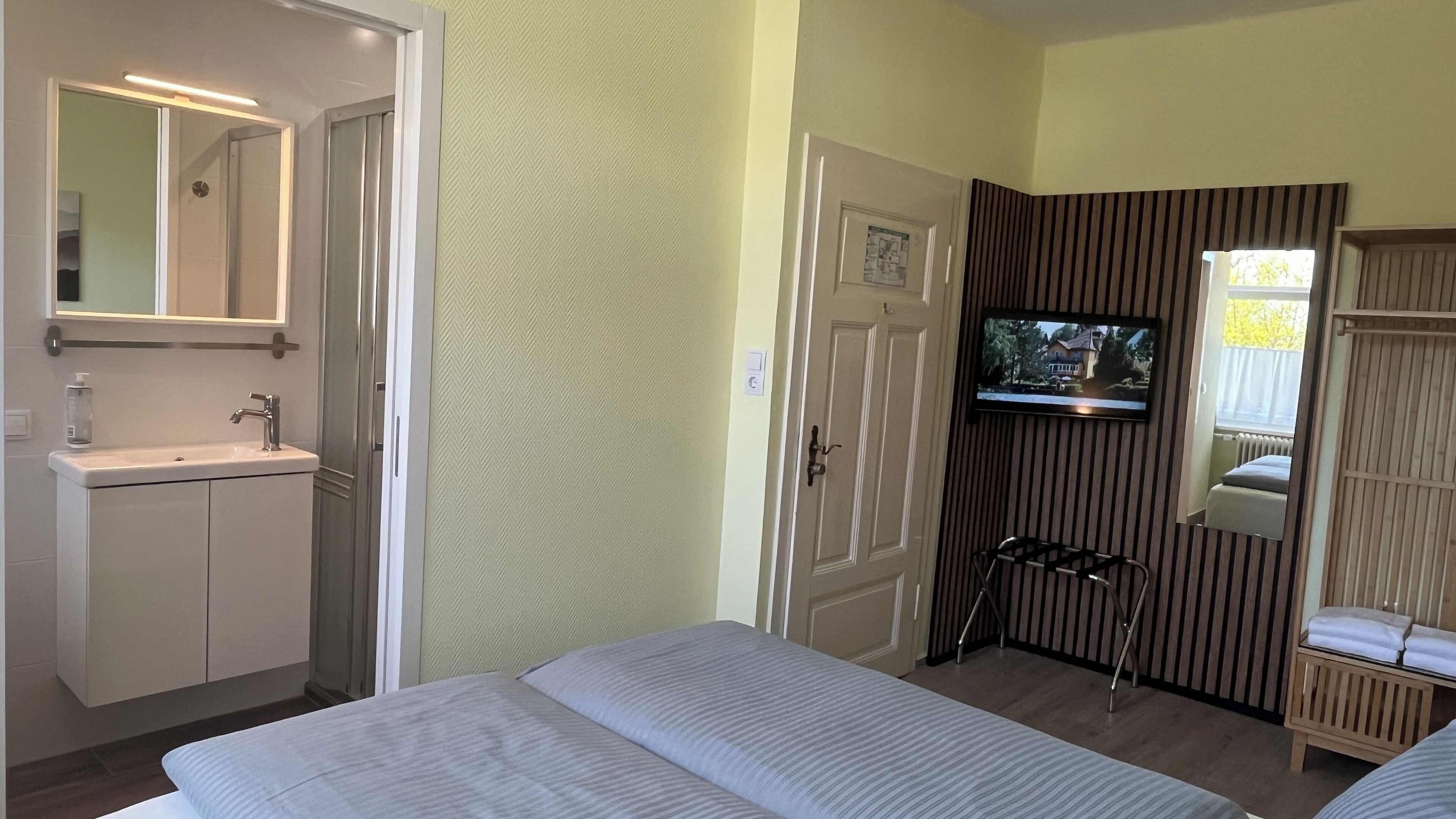 Une chambre d’hôtel comprenant un lit, une télévision, une salle de bain avec un lavabo et un miroir.