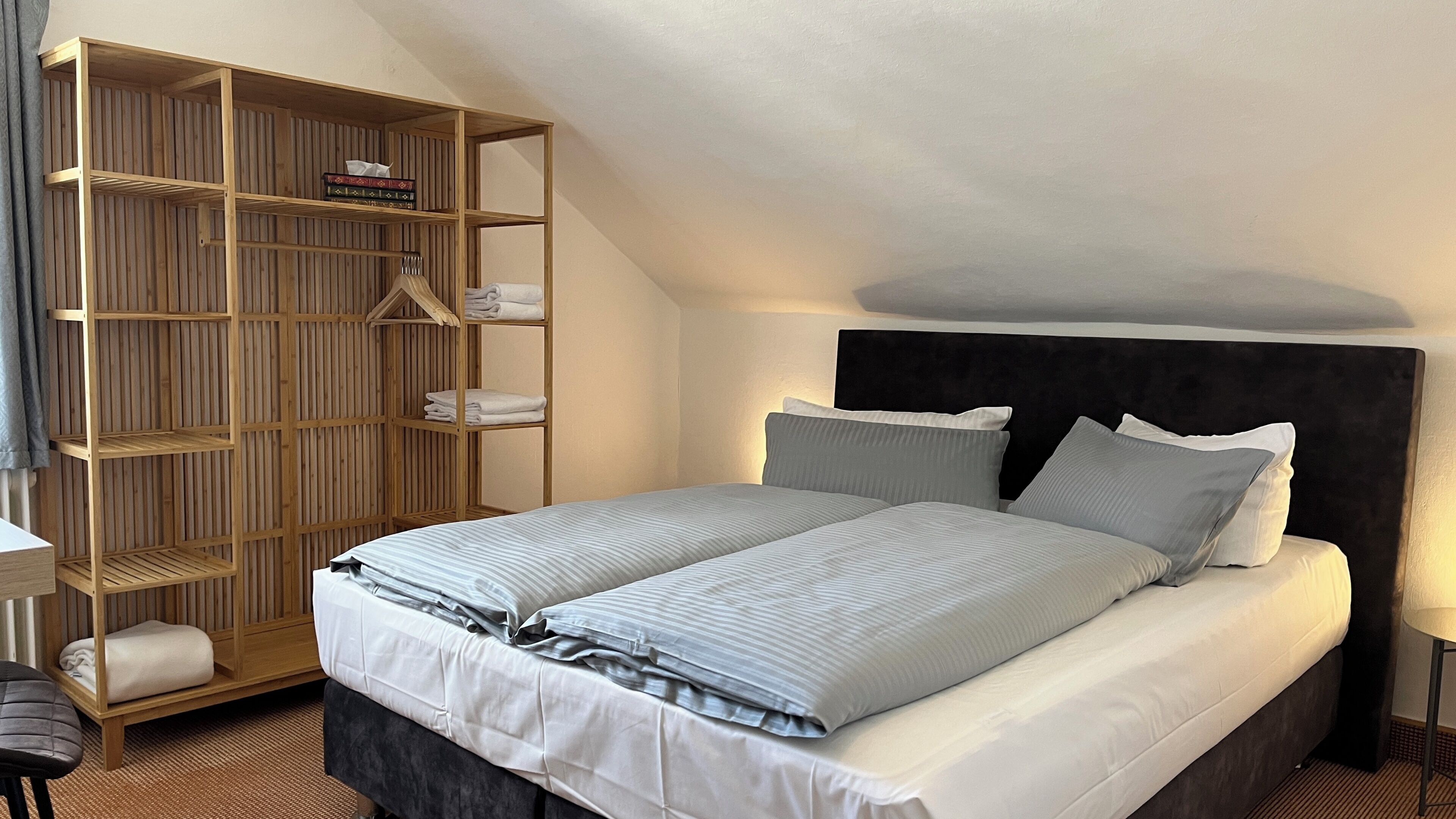 Quarto com cama, guarda-roupa de madeira e mesa de cabeceira.