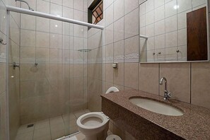 Un baño con ducha, inodoro, lavabo y espejo.