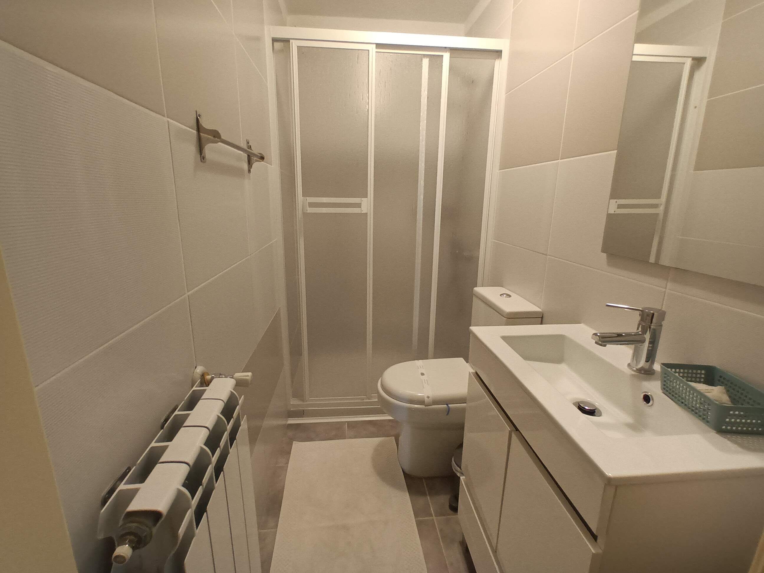 Casa de banho pequena e compacta, com chuveiro, sanita e lavatório.