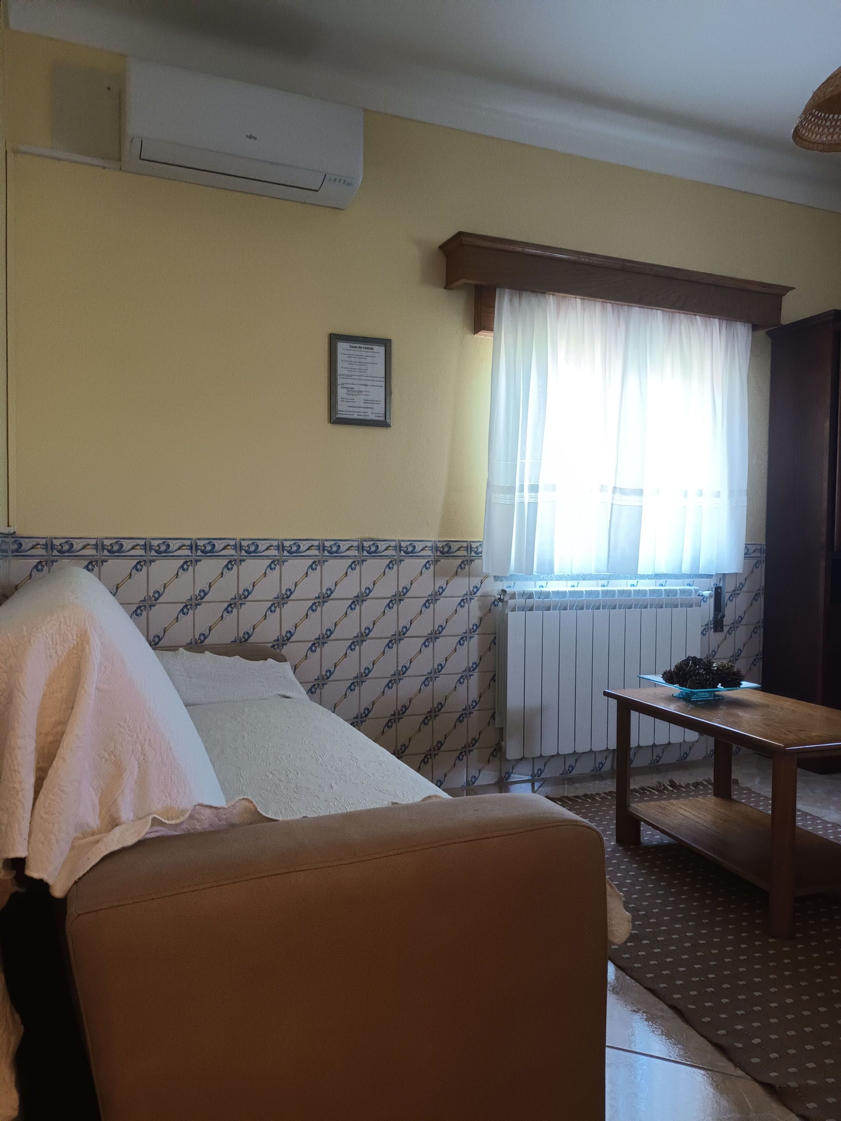 Een kamer met een bed, een tafel, een radiator en een raam met gordijnen.
