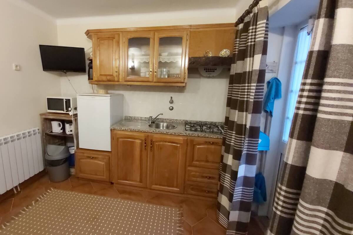 Une cuisine de taille réduite, dotée de meubles de rangement en bois, d’un four à micro-ondes, d’un réfrigérateur et d’un évier.