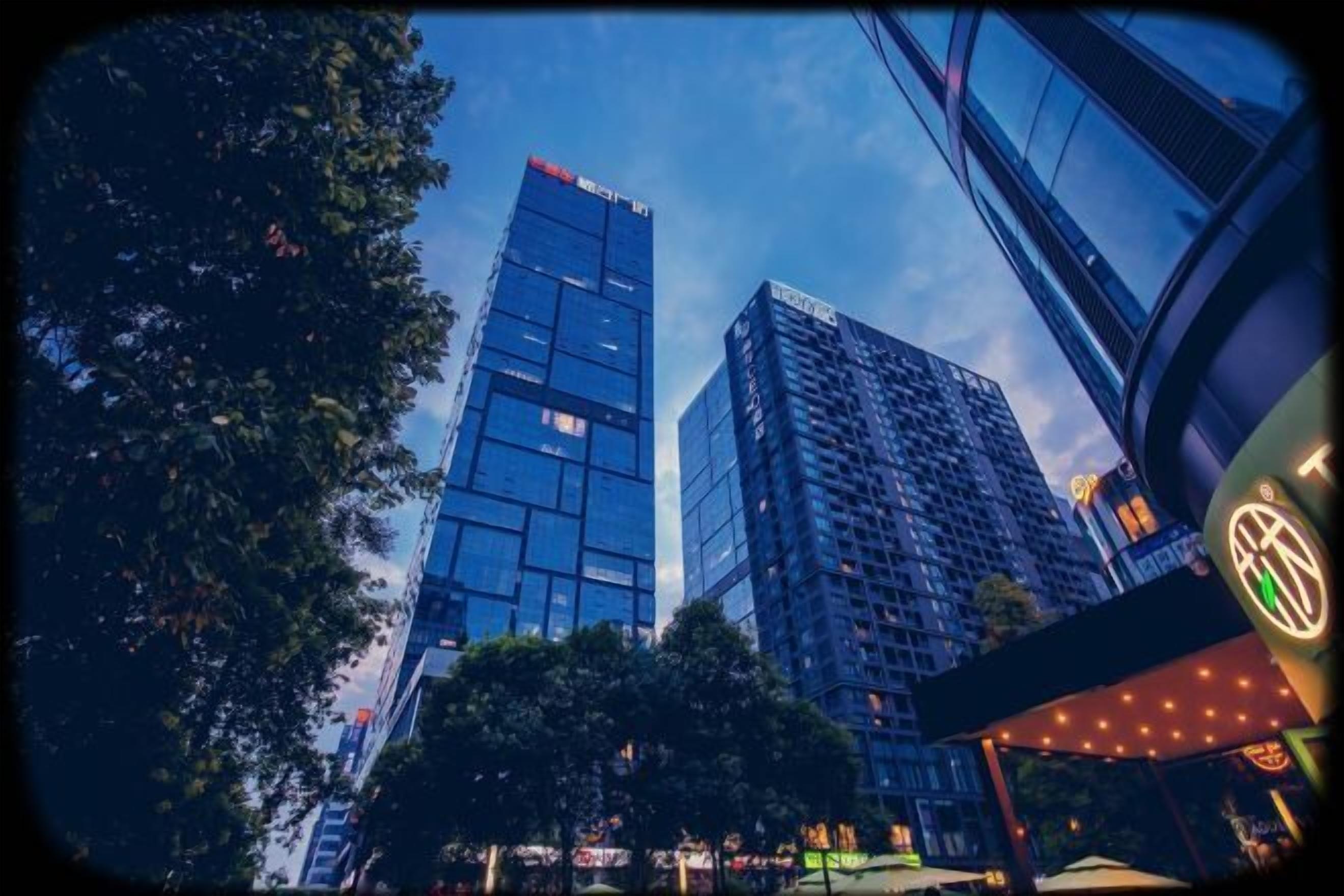 A cityscape with modern high-rise buildings, a clear sky, and a well-lit urban area.