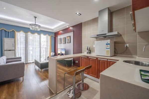 A modern kitchen with a central island, wooden cabinets, and a stainless steel sink. - Westcare Hotel (Century City New Convention and Exhibition Center Tianfu 3rd Street Store) (Chengdu)