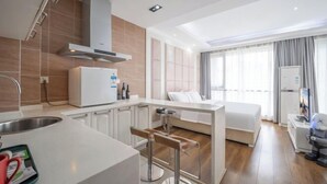 A modern hotel room with a kitchenette, a bed, a TV, and a window with curtains. - Westcare Hotel (Century City New Convention and Exhibition Center Tianfu 3rd Street Store) (Chengdu)