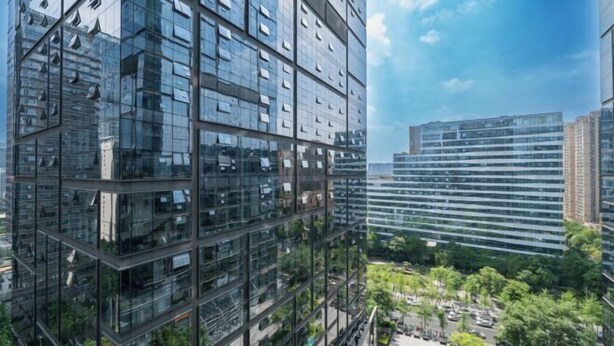 A modern high-rise building with a glass facade, surrounded by greenery and other buildings. - Westcare Hotel (Century City New Convention and Exhibition Center Tianfu 3rd Street Store) (Chengdu)