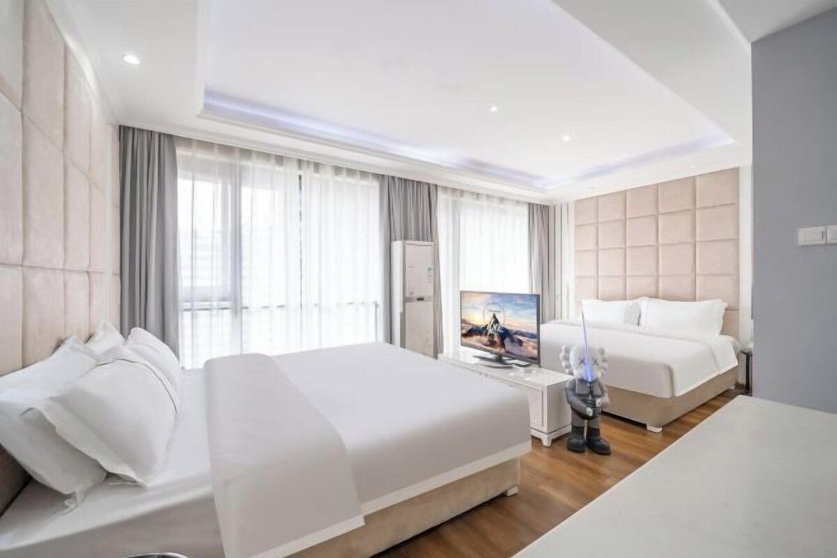 A modern hotel room with a large bed, a television, and a minibar.