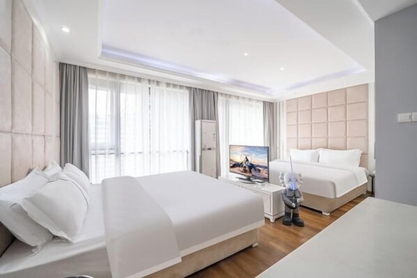 A modern hotel room with a large bed, a television, and a minibar.