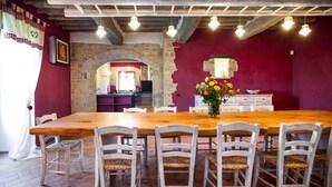 A dining area with a wooden table and white chairs, a stone archway, and a red wall. - Villa Meraviglia With Pool And Ac (Poggibonsi)