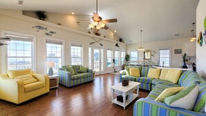 A spacious living room with a yellow sofa, striped couches, and a wooden floor. - Dive into "Summer Days & Cooler Nights"! w/ pool! (Surf City)